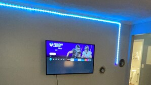 A living room with a flat-screen TV mounted on the wall, a coffee table with a vase, and a remote control. - The Music Row Getaway (Nashville)