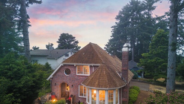 Une maison avec une façade en briques, une cheminée et une fenêtre ronde.