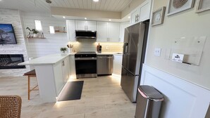 A modern kitchen with white cabinetry, stainless steel appliances, and a central island.