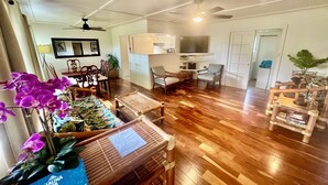 Un amplio espacio de estar con piso de madera, un comedor y un conjunto de asientos.