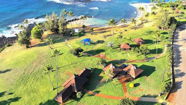 Una propiedad costera con varias edificaciones, una playa y una vista despejada del océano.