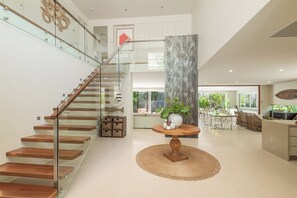 Een modern interieur met een houten trap, een ronde houten tafel met een vaas, en een eethoek met stoelen en een tafel.