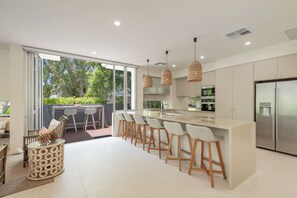 Een moderne keuken met een groot schiereiland, barstoelen en uitzicht op de omgeving.
