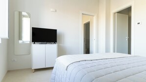 Une chambre à coucher avec un lit, un téléviseur posé sur un meuble, un miroir et une armoire.