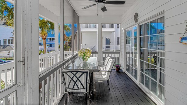 Ein überdachter Balkon mit Deckenventilator, einem Glastisch und Stühlen.