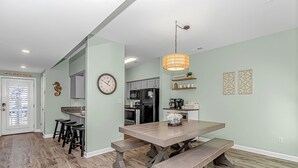 Eine moderne Küche mit Essbereich, ausgestattet mit einem Holztisch, Bänken und einer Pendelleuchte.