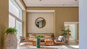 Un amplio salón con un gran ventanal, un espejo redondo en la pared y un conjunto de sofás.
