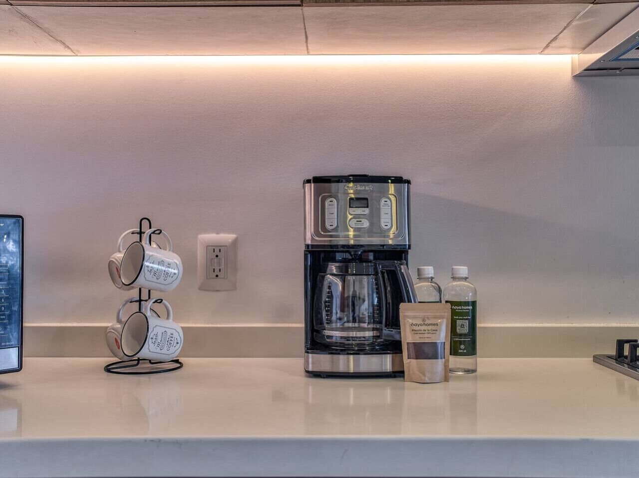 A coffee machine, a mug rack, and two bottles of water on a countertop.