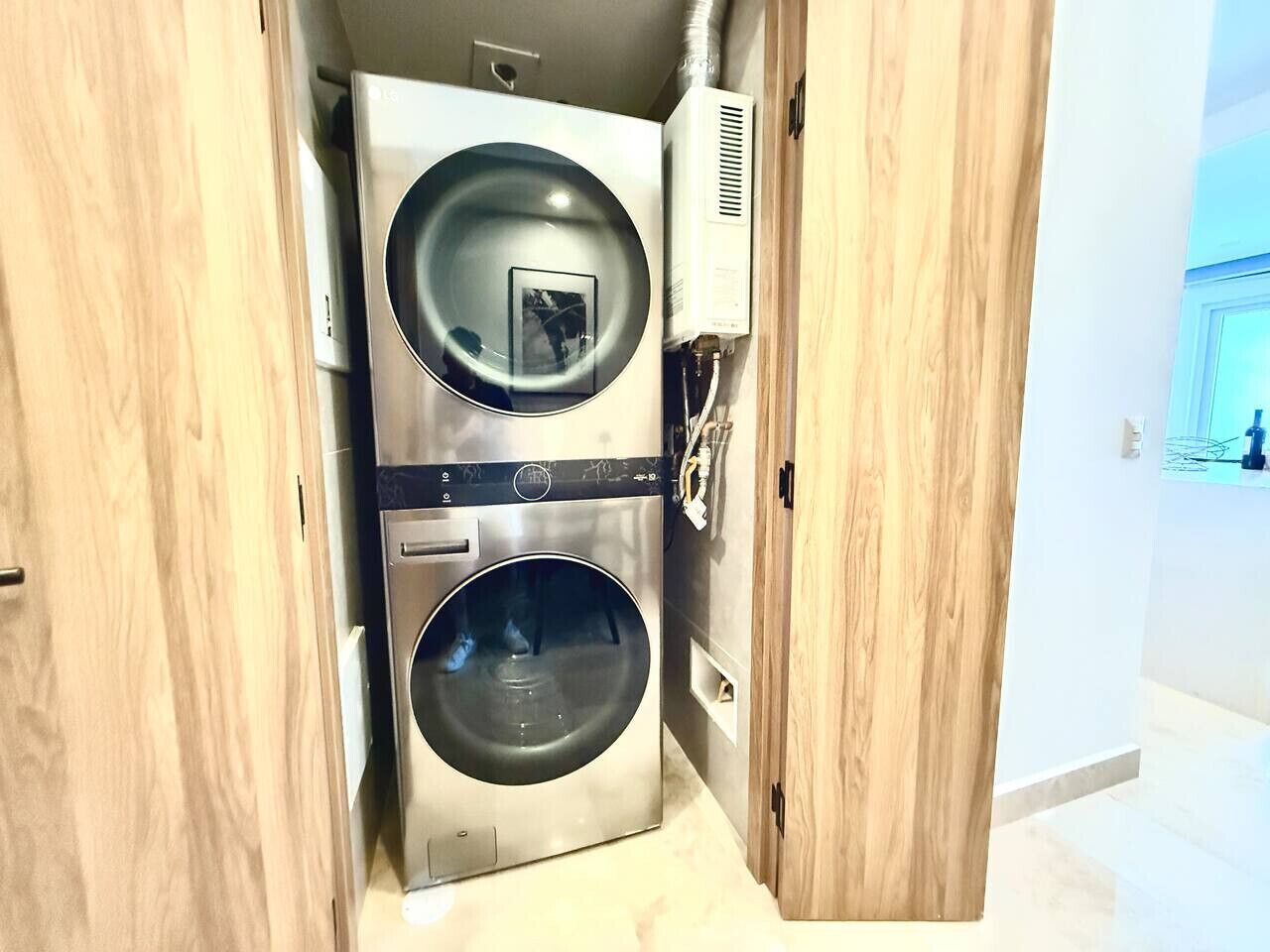 Une petite buanderie équipée de deux lave-linge à chargement frontal en acier inoxydable et d’un sèche-linge fixé au mur.