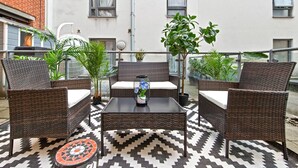 A balcony with wicker furniture, a patterned rug, and potted plants. - Liverpool Street Retreat (London)
