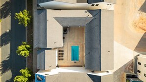 Vista aérea de un edificio moderno con entrada central, piscina y zona exterior cubierta.