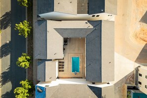 Vista aérea de un edificio moderno con entrada central, piscina y zona exterior cubierta.