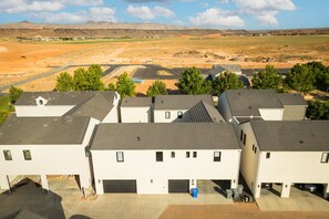 Un barrio residencial con varias casas de una sola planta, cada una con garaje, frente a un paisaje desértico con montañas al fondo.