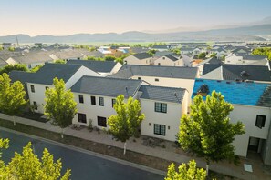A residential area with modern houses, a swimming pool, and a clear view of distant mountains. - Brand New Home! Its about time to have a beautiful pool area, spacious 7 bedroom home. (Hurricane)