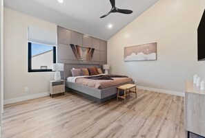 A modern bedroom with a bed, bedside tables, a ceiling fan, and a window with blinds. - Brand New Home! Its about time to have a beautiful pool area, spacious 7 bedroom home. (Hurricane)