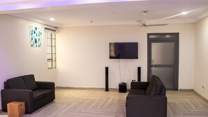 A modern living room with two sofas, a flat-screen TV, and a door.