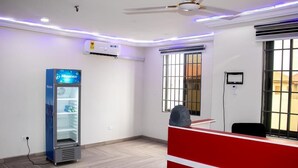 A modern office space with a vending machine, a ceiling fan, and a window with bars.