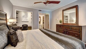 A bedroom with a large bed, a dresser, a mirror, and a ceiling fan. - The Two-Step Retreat : Poolside Comfort Near Arlington (Grand Prairie)