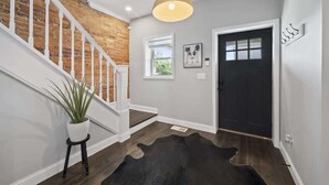 A staircase with white railings and a brick wall, a black door, and a small potted plant. - Hot Tub-Sauna-Bar-Gym-4BR-Sleeps 8 (Columbus)