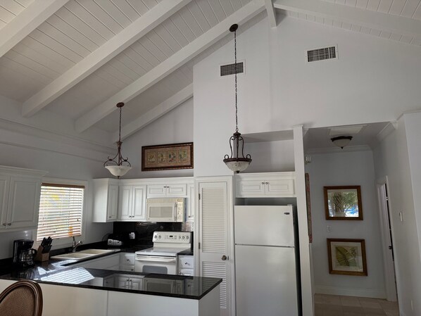 A kitchen with white cabinetry, a central island, a stove, and a refrigerator.