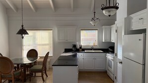 A kitchen with white cabinets, a black countertop, and a white refrigerator. - Cottage 6 - Charming 1-bedroom cottage-pool-tennis-walk to beach in Sandy Point (Sandy Point)