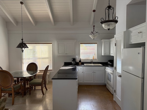 A kitchen with white cabinets, a black countertop, and a white refrigerator. - Cottage 6 - Charming 1-bedroom cottage-pool-tennis-walk to beach in Sandy Point (Sandy Point)