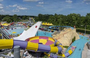 Parque acuático con múltiples toboganes y piscinas, rodeado de árboles.