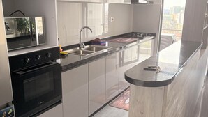 A modern kitchen with stainless steel appliances, a large window, and a view of the city. - Luxury living in Kilimani perfect for families or business trips (Nairobi)