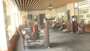 A gym with various exercise machines, large windows, and a wooden ceiling. - Luxury living in Kilimani perfect for families or business trips (Nairobi)
