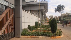 A modern building with a gated entrance, paved walkway, and landscaped garden area. - Luxury living in Kilimani perfect for families or business trips (Nairobi)
