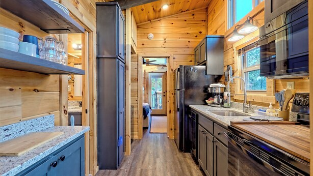 A modern kitchen with wooden walls, granite countertops, and stainless steel appliances.