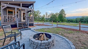 A wooden cabin with a porch, outdoor seating, and a fire pit.