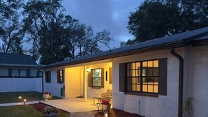 A residential house with a paved driveway, a front porch, and a well-lit entrance. - The Seminole Heights Suncatcher - Pool & Basketball (Tampa)