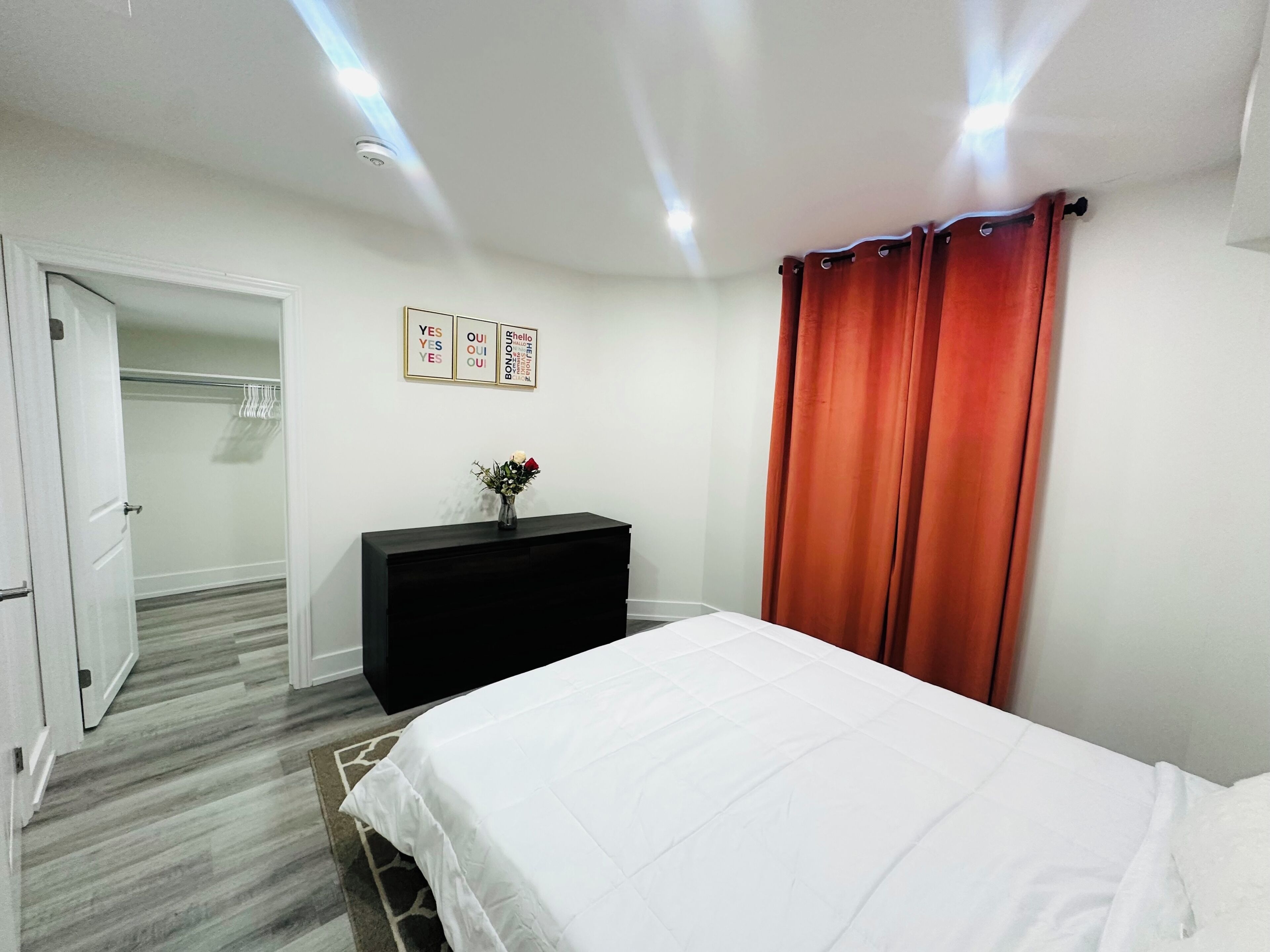 Une chambre à coucher comprenant un lit, une commode, un placard et un mur orné de trois panneaux encadrés.