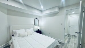 Une chambre à coucher avec un grand lit, une table de chevet avec une lampe, un miroir et une porte.