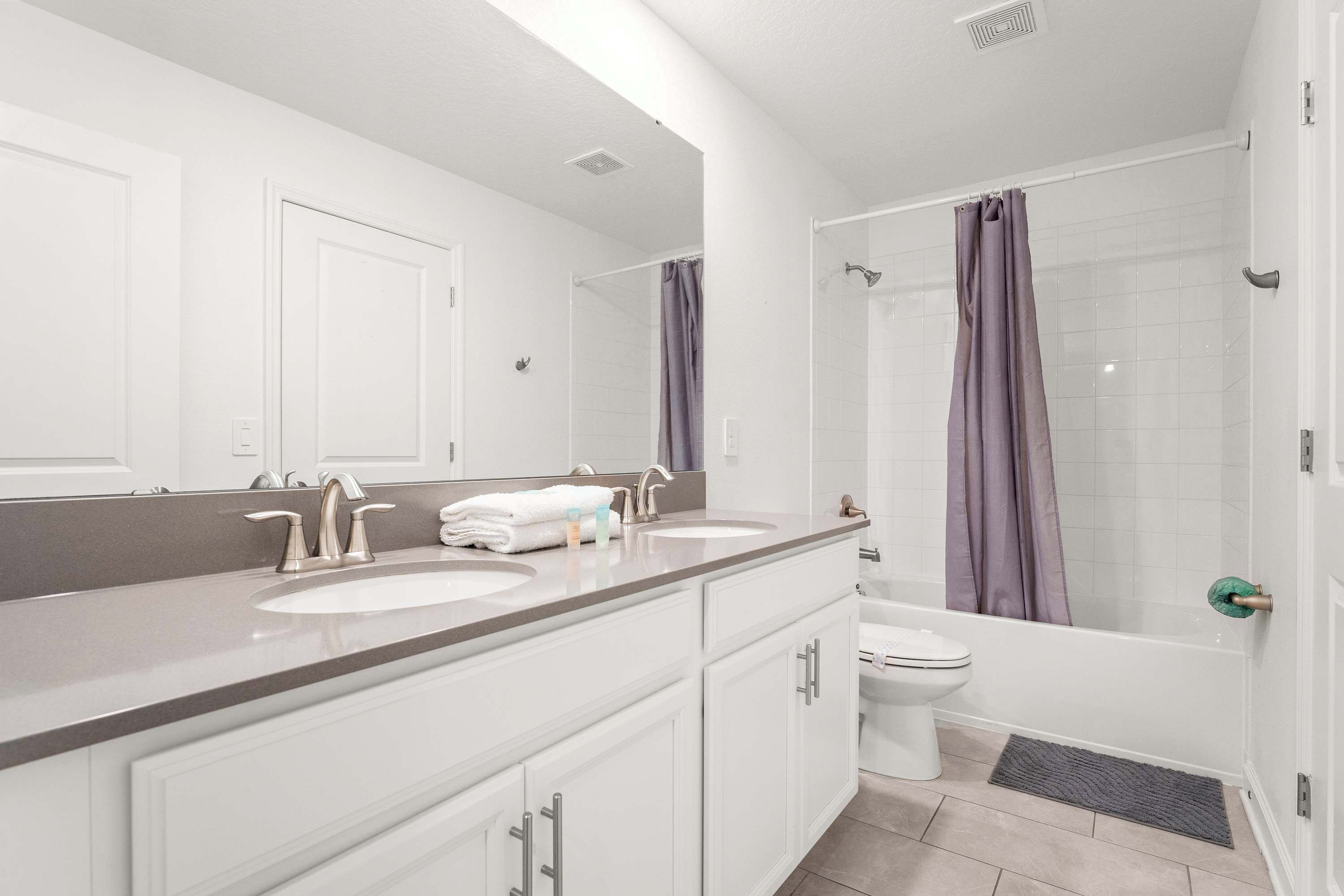A modern bathroom with two sinks, a toilet, and a shower.