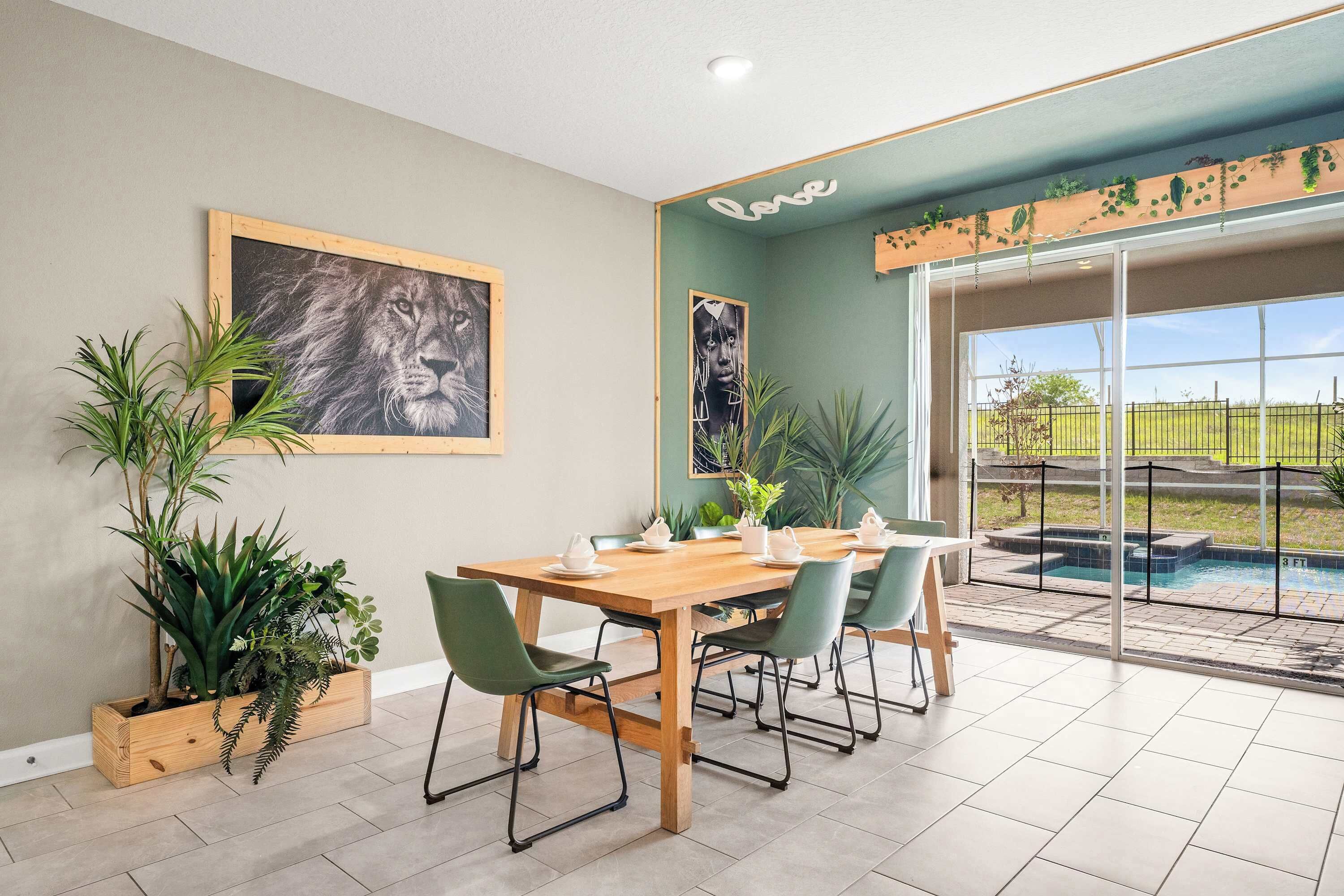 A dining area with a wooden table, green chairs, and potted plants.