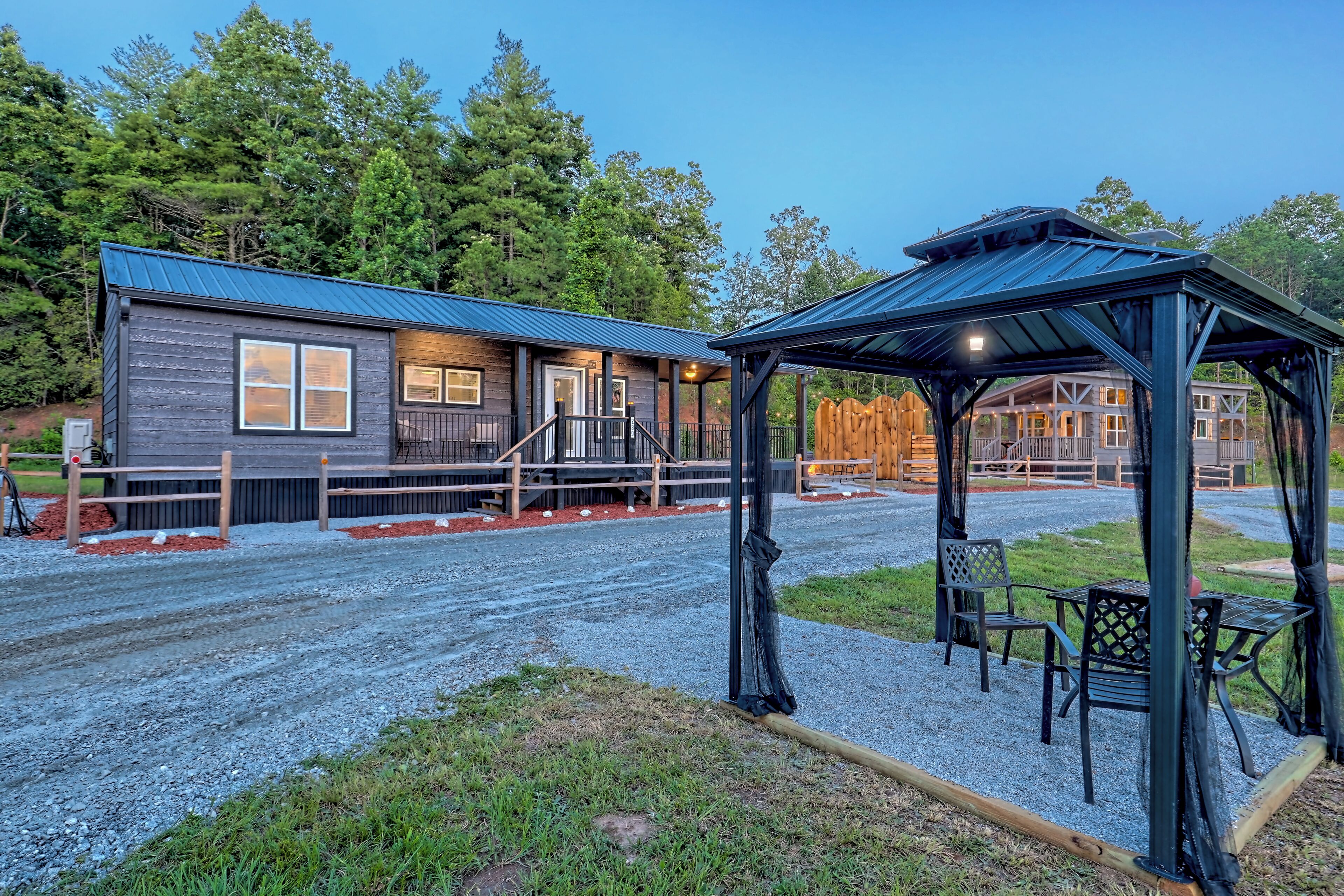 A rustic cabin with a metal roof, wooden deck, and a covered outdoor seating area.