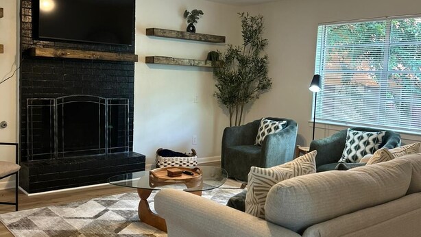 Un salon avec une cheminée, un canapé, une table basse et un ventilateur de plafond.