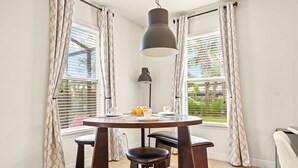 A dining area with a round table, two stools, a pendant light, and curtains on windows. - Solterra Bliss - Resort Stay for 13 w/ Pool, Hot Tub & Game Room (Davenport)