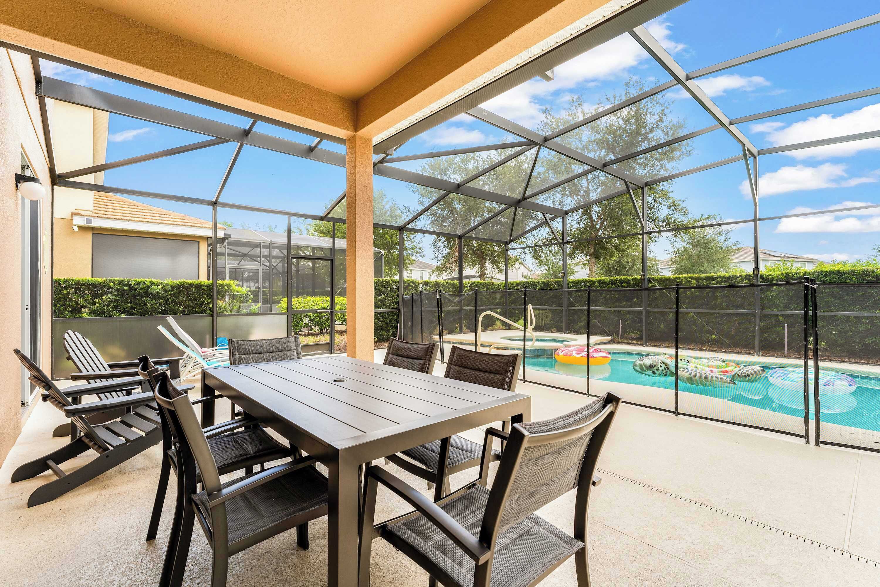 Eine Terrassengaststätte mit Tisch und Stühlen, ein Pool mit aufblasbaren Spielzeugen und Blick auf die Nachbarschaft.