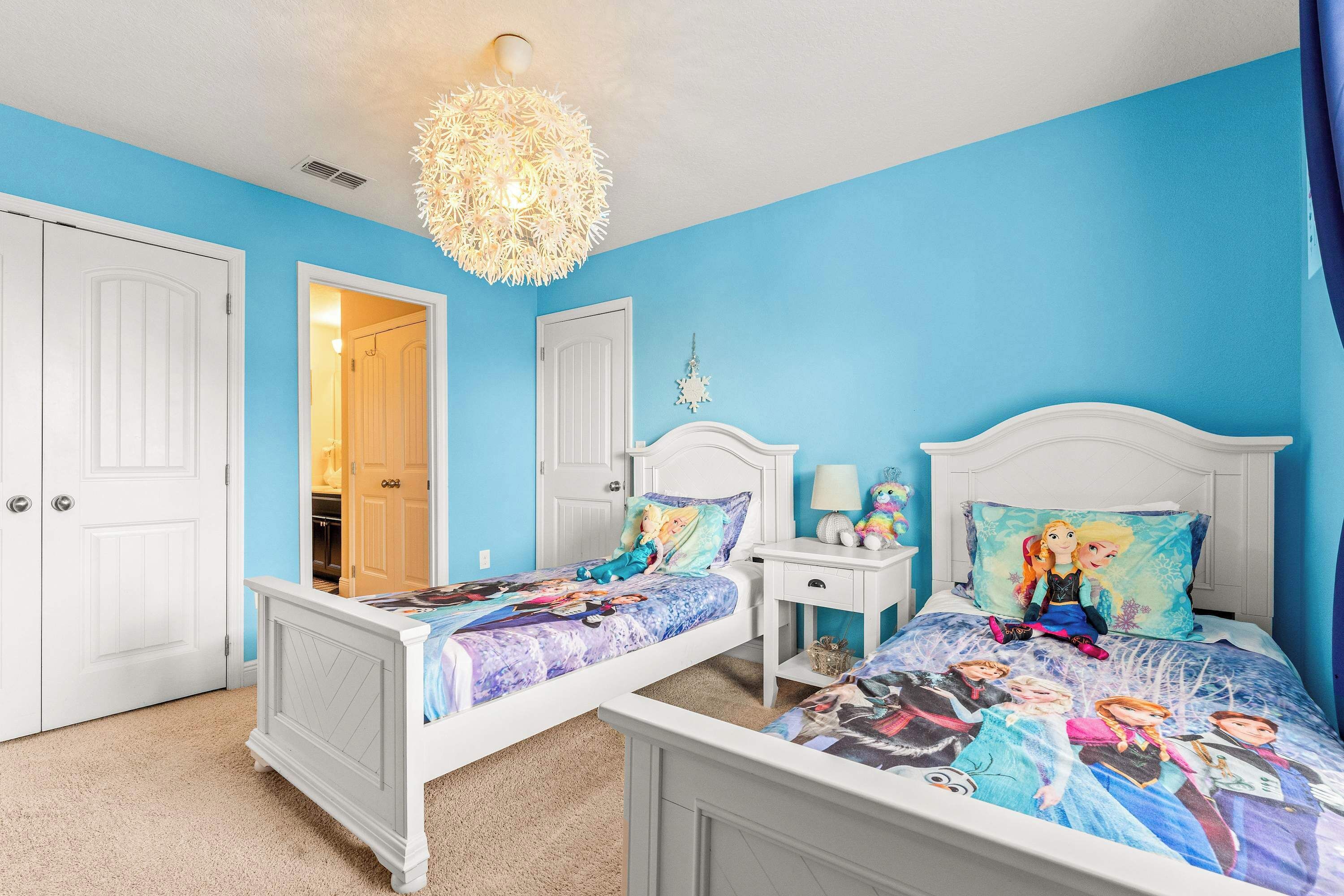 Ein Schlafzimmer mit zwei Betten, einer Chandelüster und einer blauen Wand.