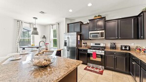 A modern kitchen with dark cabinets, stainless steel appliances, and a granite countertop. - Solterra Bliss - Resort Stay for 13 w/ Pool, Hot Tub & Game Room (Davenport)