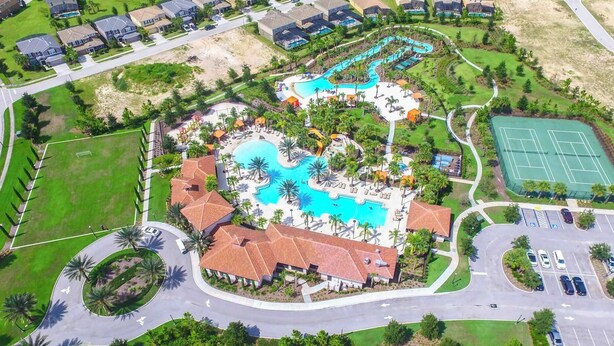 An aerial view of a resort with a large central pool, multiple smaller pools, a tennis court, and a parking area. - Solterra Bliss - Resort Stay for 13 w/ Pool, Hot Tub & Game Room (Davenport)