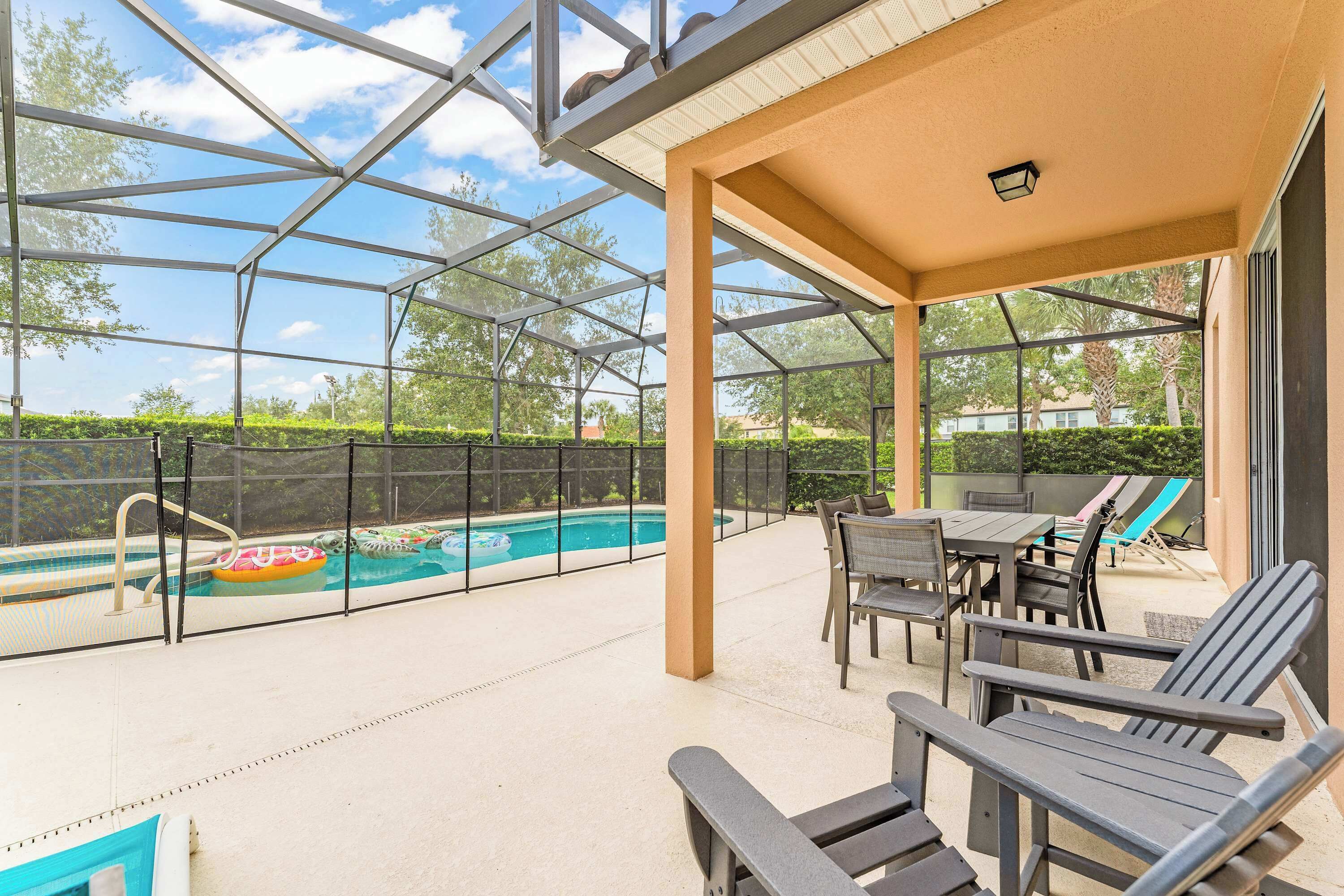 A covered outdoor area with a pool, lounge chairs, and a table.