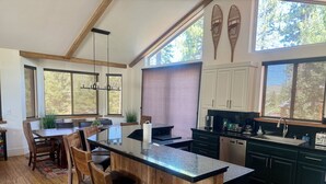 Una cocina moderna con armarios de madera, una isla grande con asientos y ventanas amplias que proporcionan luz natural.