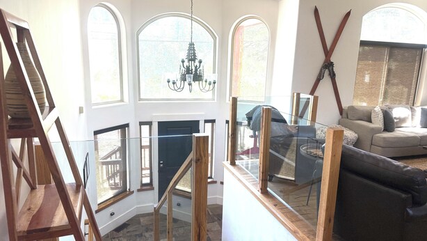 Un amplio salón con escaleras, una araña y un sofá.