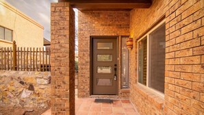 A brick exterior with a door, a window, and a stone wall. - Cozy Home w/Private Patio, KingBed, Fireplace, BBQ (El Paso)