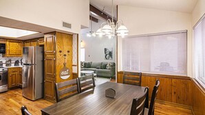 A modern kitchen with wooden cabinets, a stainless steel refrigerator, and a dining area with a wooden table and chairs. - Cozy Home w/Private Patio, KingBed, Fireplace, BBQ (El Paso)