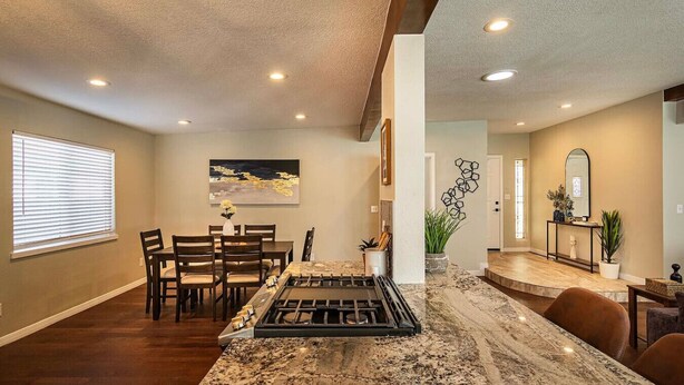A modern kitchen with a granite countertop, dining area with chairs, and a living space with a fireplace. - Family Home w/ Outdoor Playground, Patio, King Bed (El Paso)